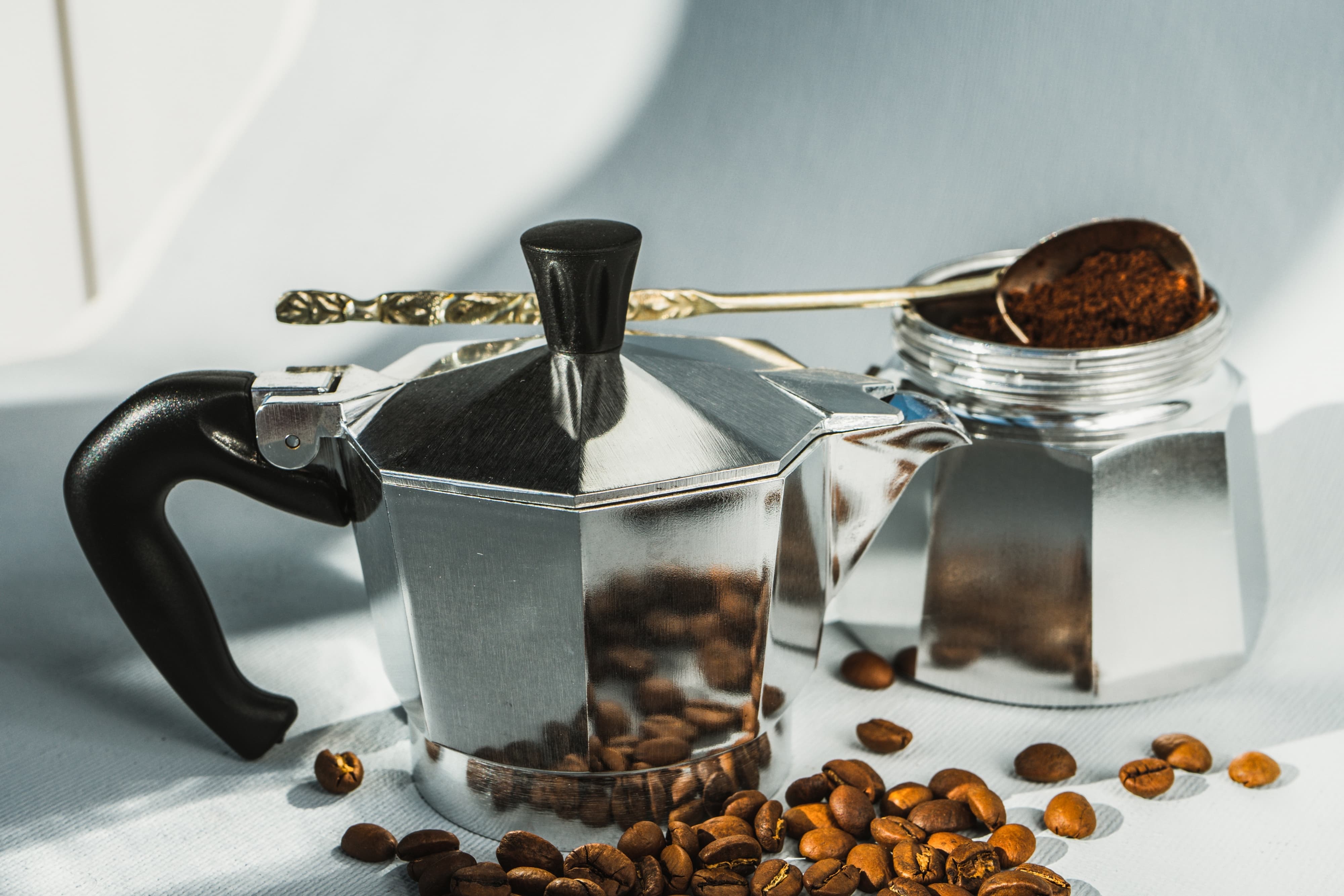 Italienische Mokkakanne Klassische silberne Mokkakanne mit Kaffeepulver und Kaffeebohnen.
