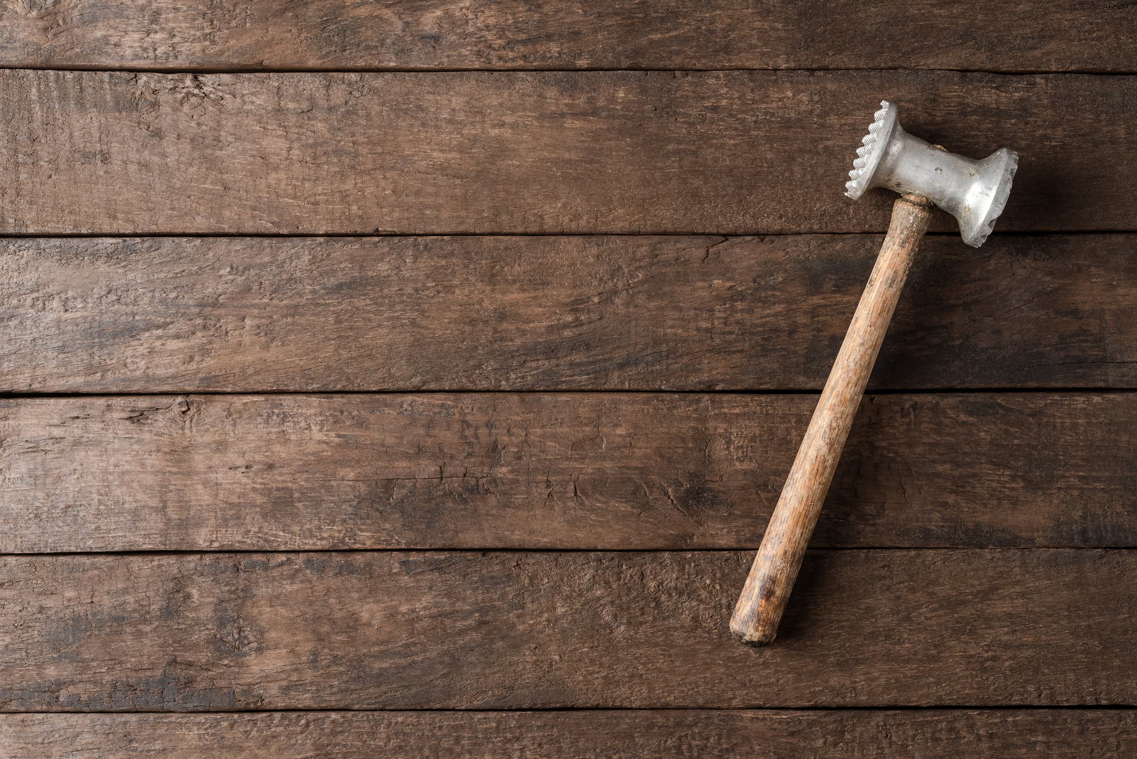 Holzhammer auf rustikalem Tisch Kuechenholzhammer auf rustikalem braunen Holztisch liegend, Draufsicht.