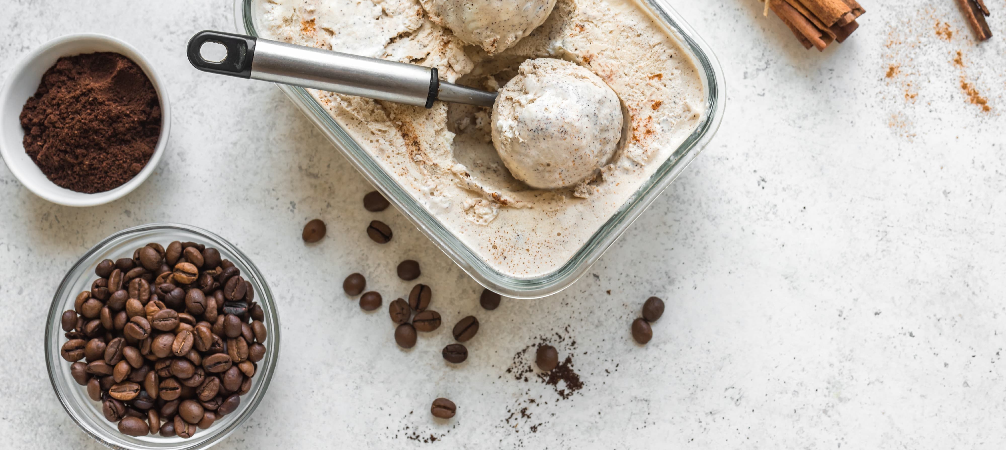Glasform mit Kaffee-Eiscreme, daneben Schüssel mit Kaffeebohnen und gemahlenem Kaffee.
