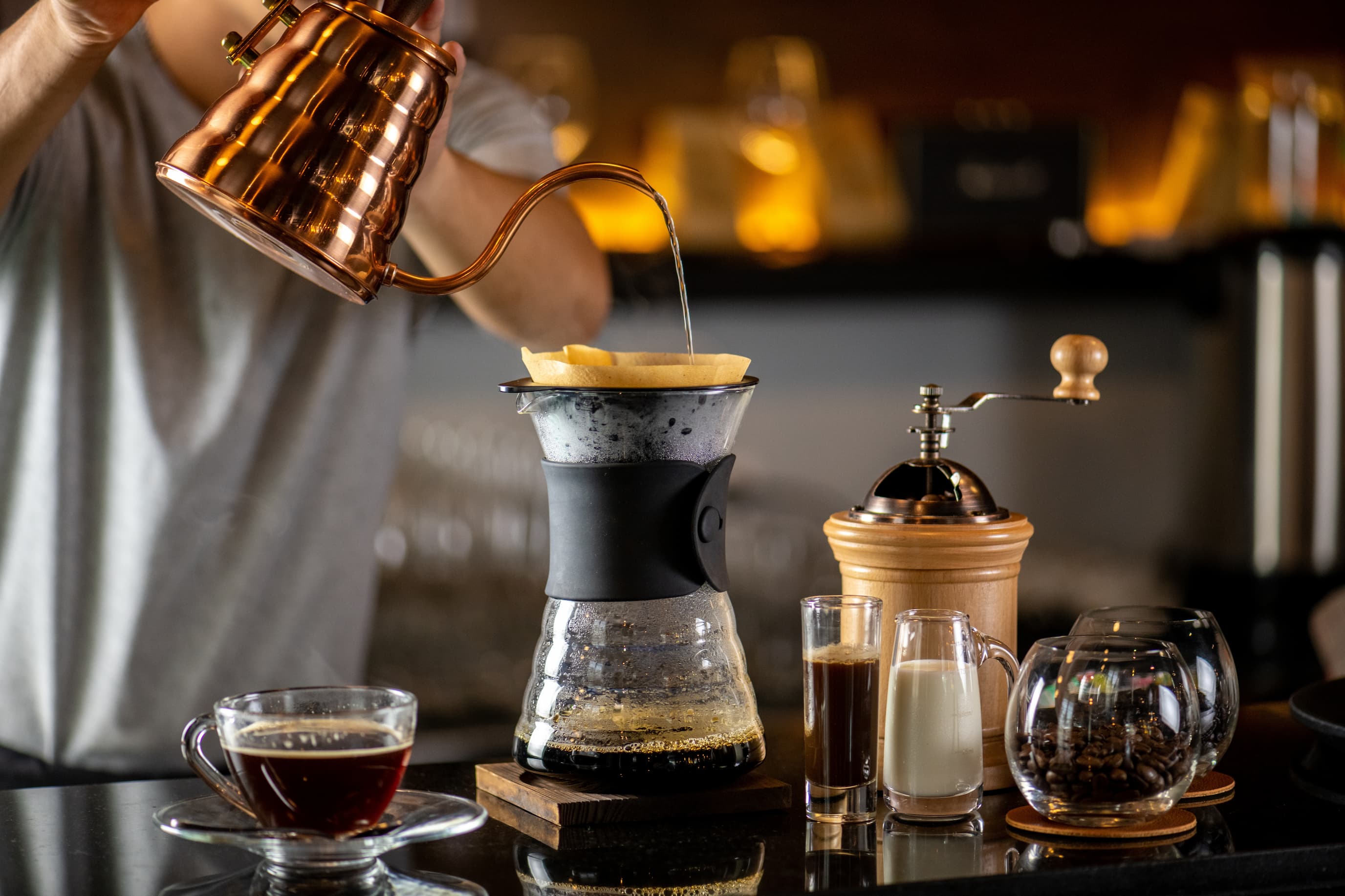 Pour Over Kaffeezubereitung Barista bereitet Pour Over Kaffee mit Handfilter, Wasserkessel und Glaskanne zu.