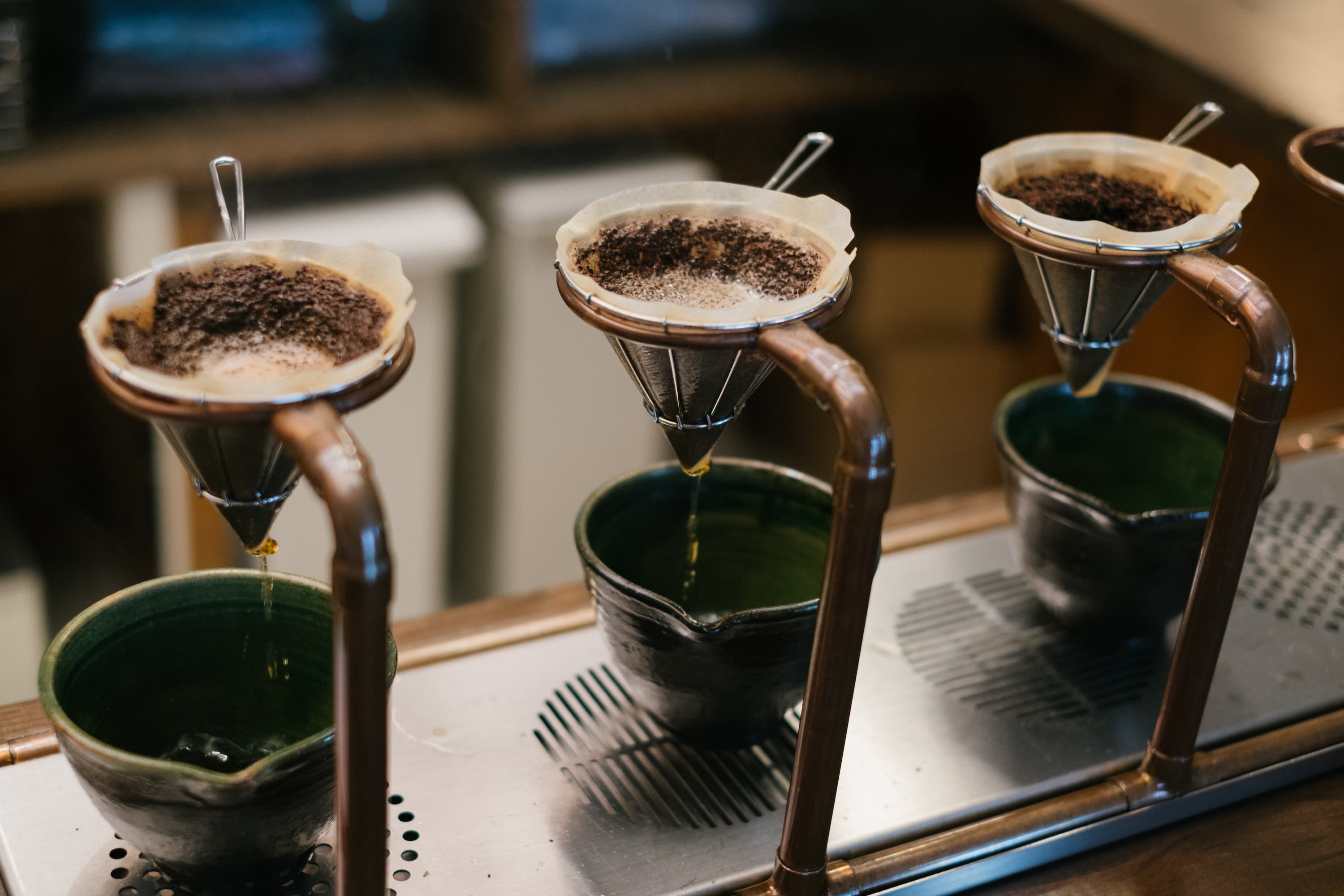 Handaufguss mit Kaffeefilter Mehrere Handaufguss-Kaffeefilter mit frischem Kaffeepulver, durch die Wasser tropft.