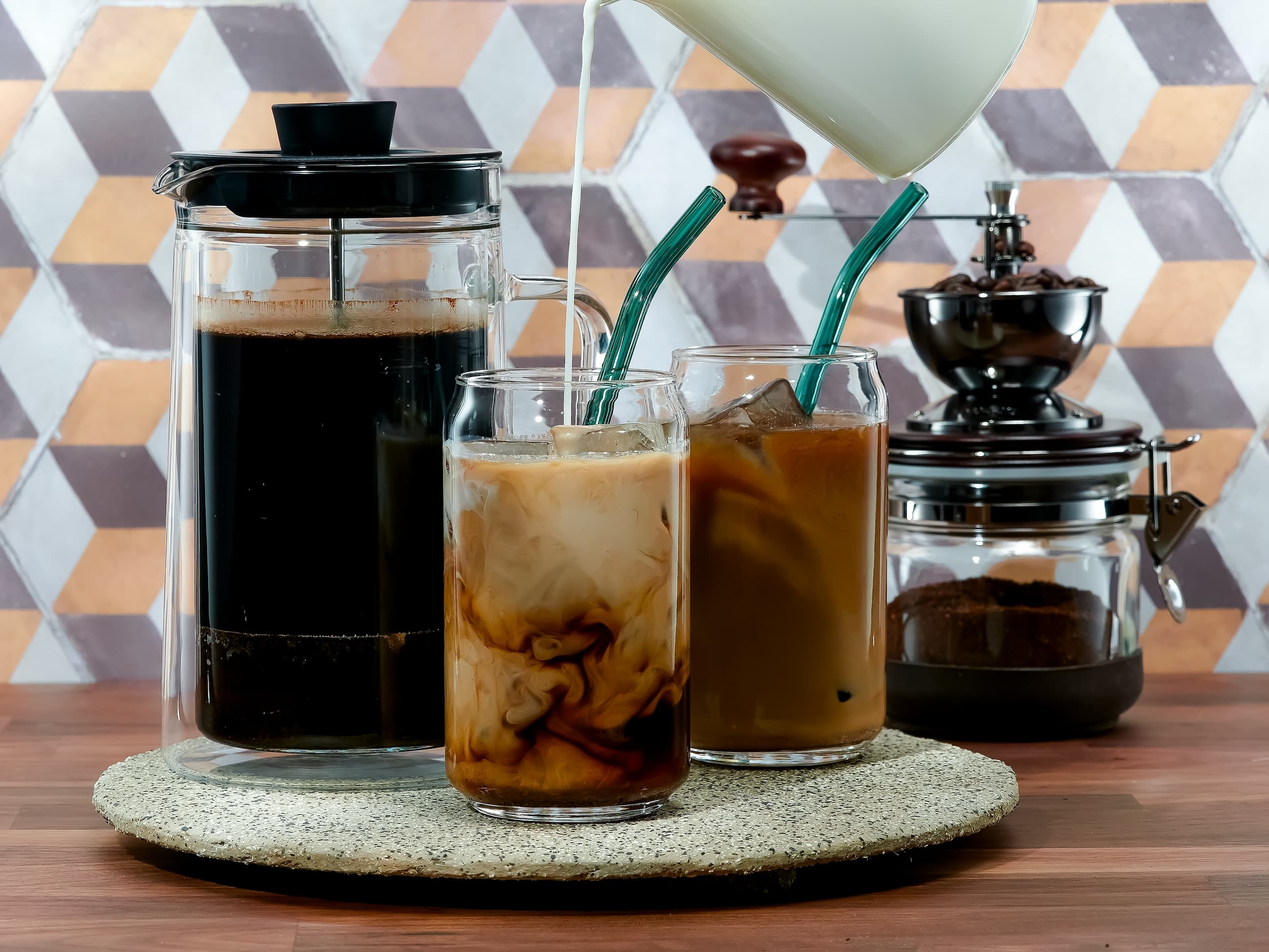 Iced Coffee Zubereitung Frisch zubereiteter Iced Coffee mit Milch, serviert in Gläsern mit Strohhalmen.