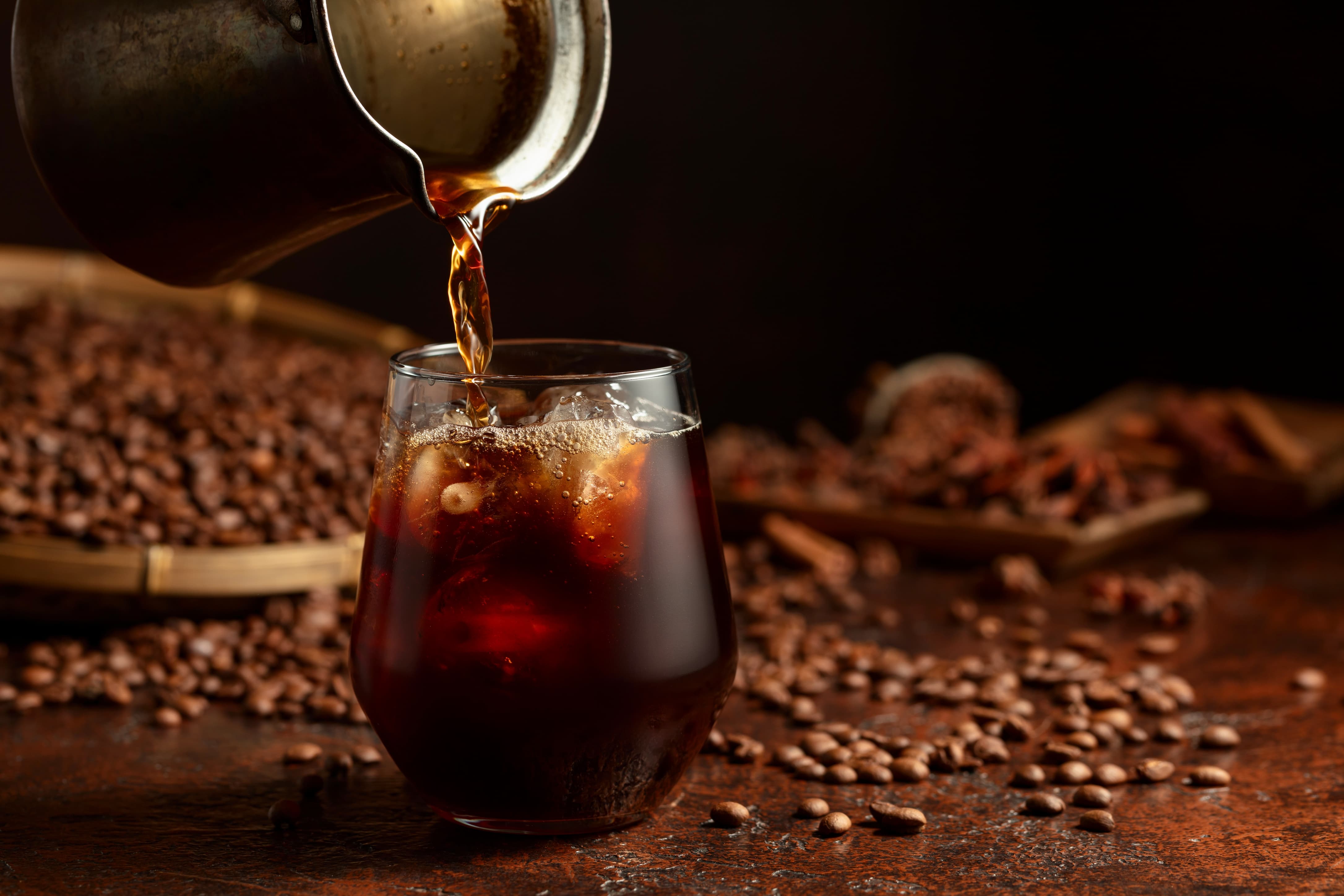 Cold Brew Kaffee Eisgekühlter Cold Brew Kaffee wird in ein Glas mit Eiswürfeln gegossen.