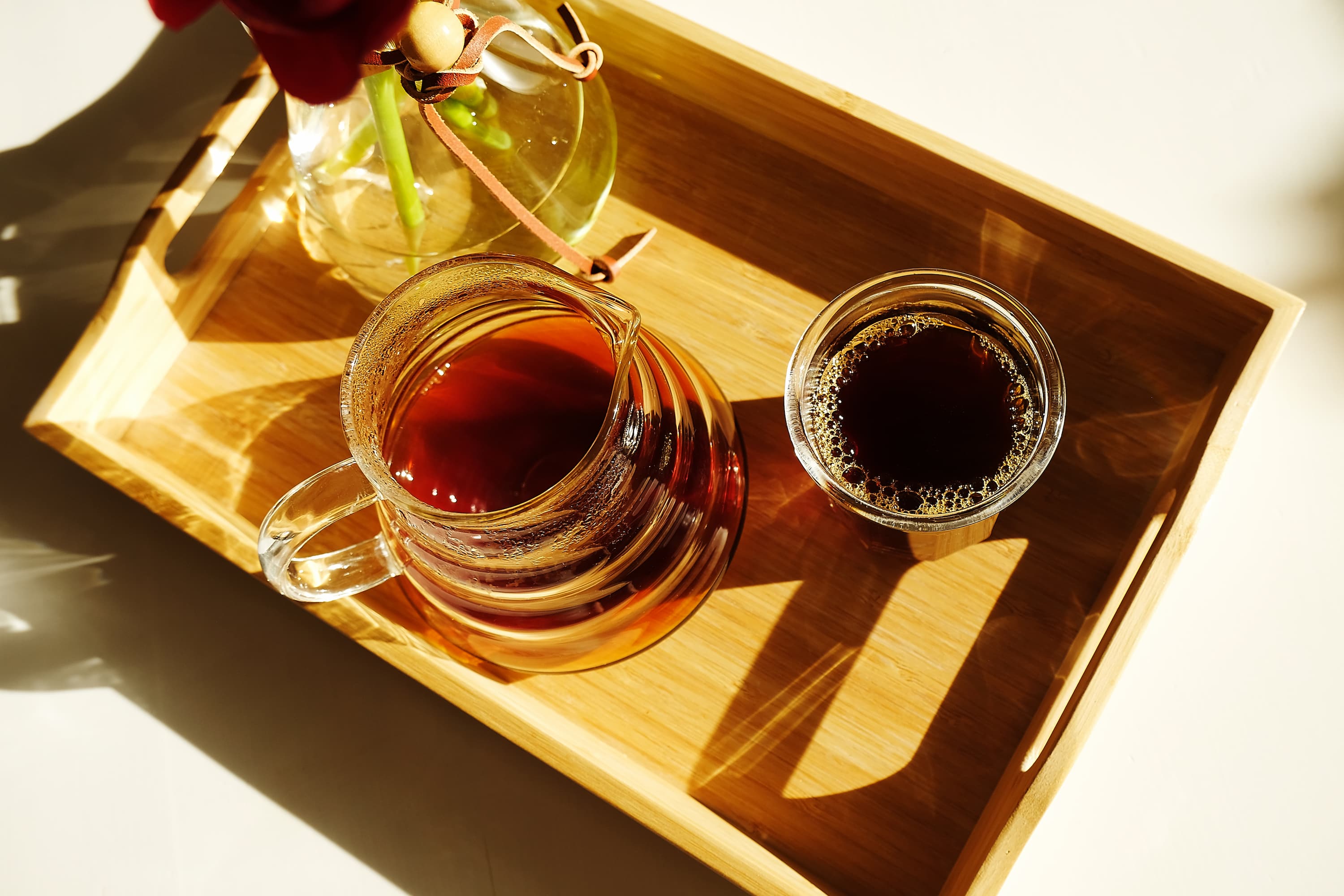Kaffee auf Holztablett serviert Glaskanne und Glas mit Kaffee auf Holztablett im Sonnenlicht serviert.