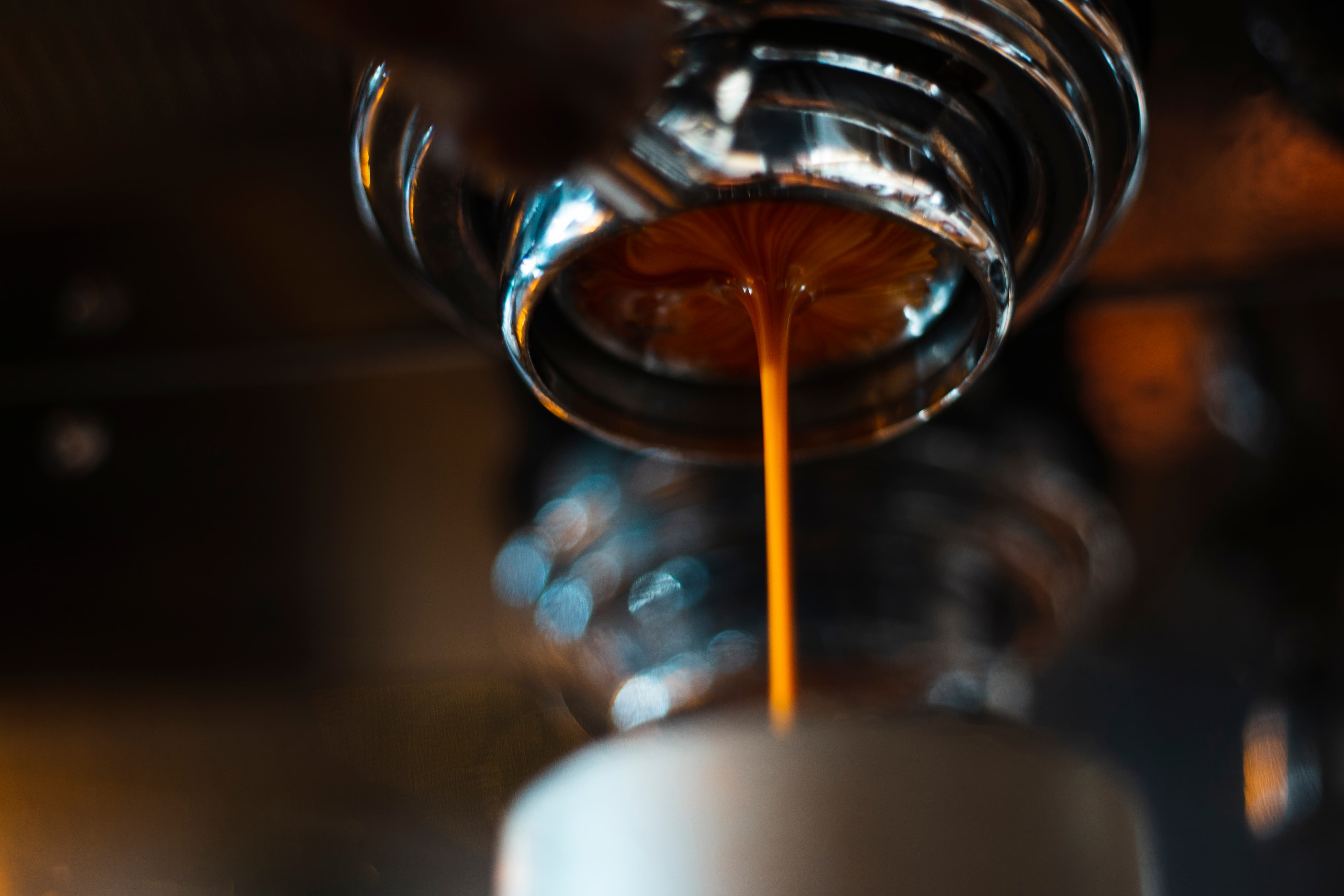 Espresso-Extraktion Nahaufnahme Frisch gebruehter Espresso laeuft aus einer Siebtraegermaschine in eine Tasse, Nahaufnahme.