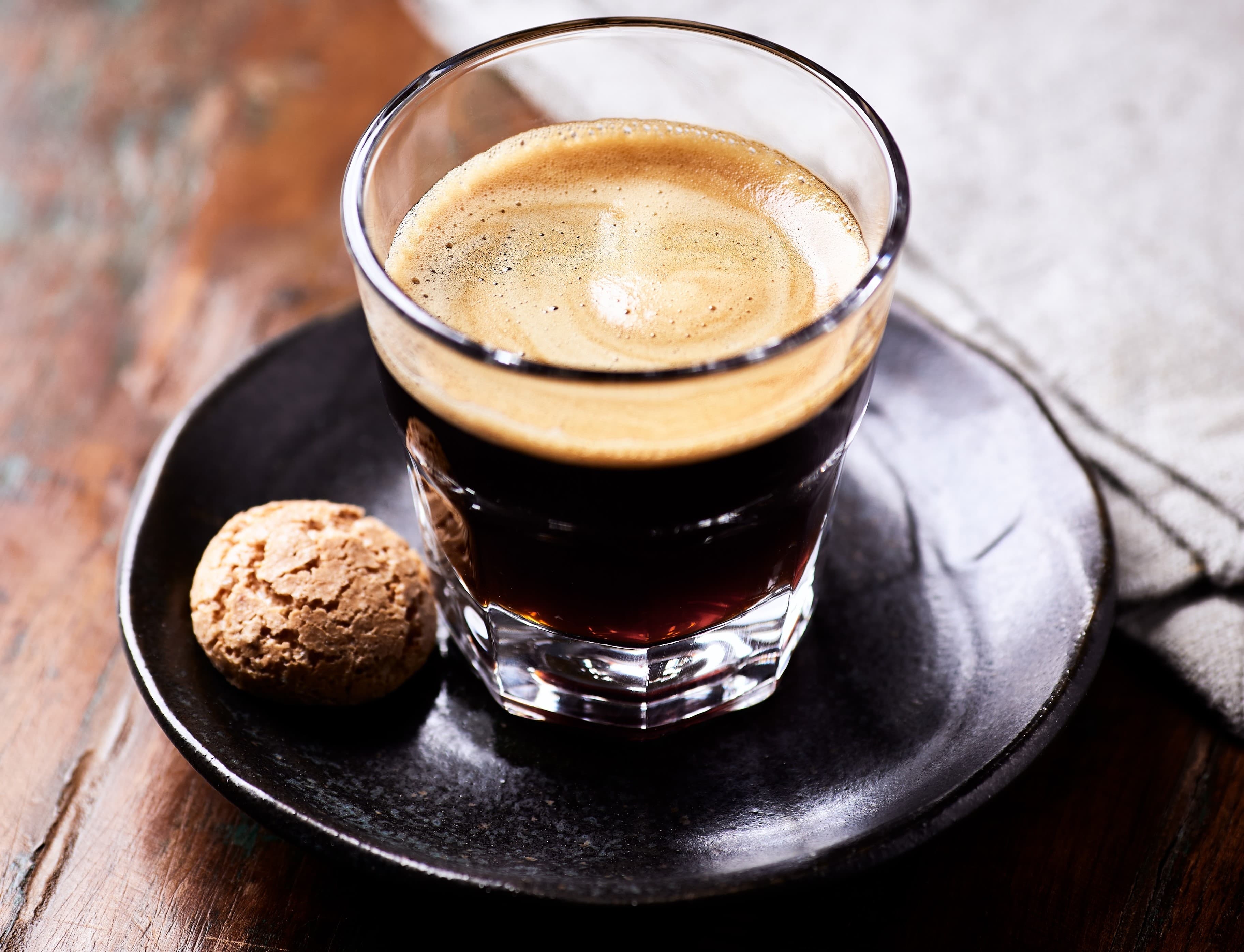 Espresso mit Keks Frisch gebrühter Espresso im Glas, serviert auf Teller mit Keks.