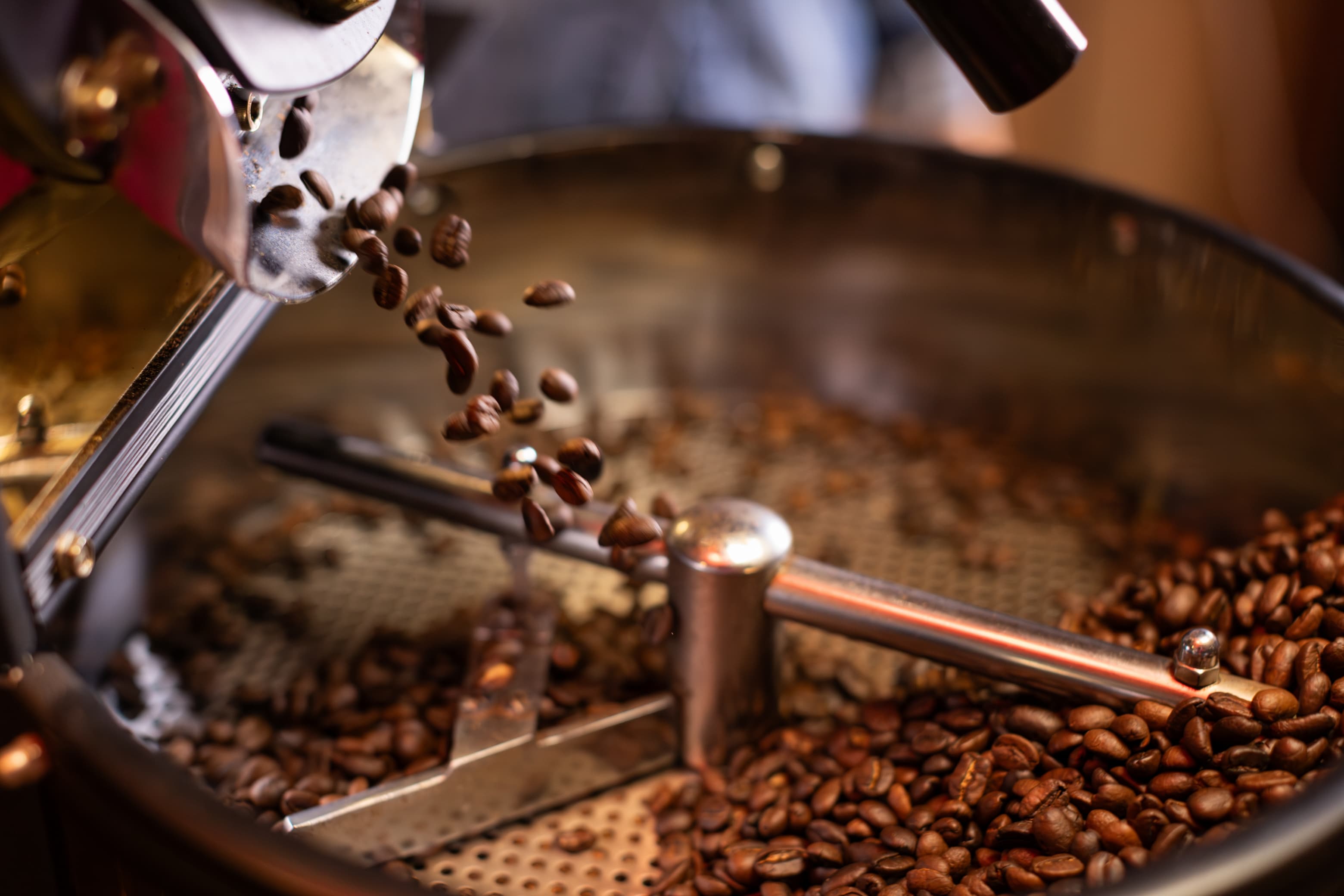 Kaffeebohnen in der Röstmaschine Frisch geröstete Kaffeebohnen fallen aus der Trommelröstmaschine.