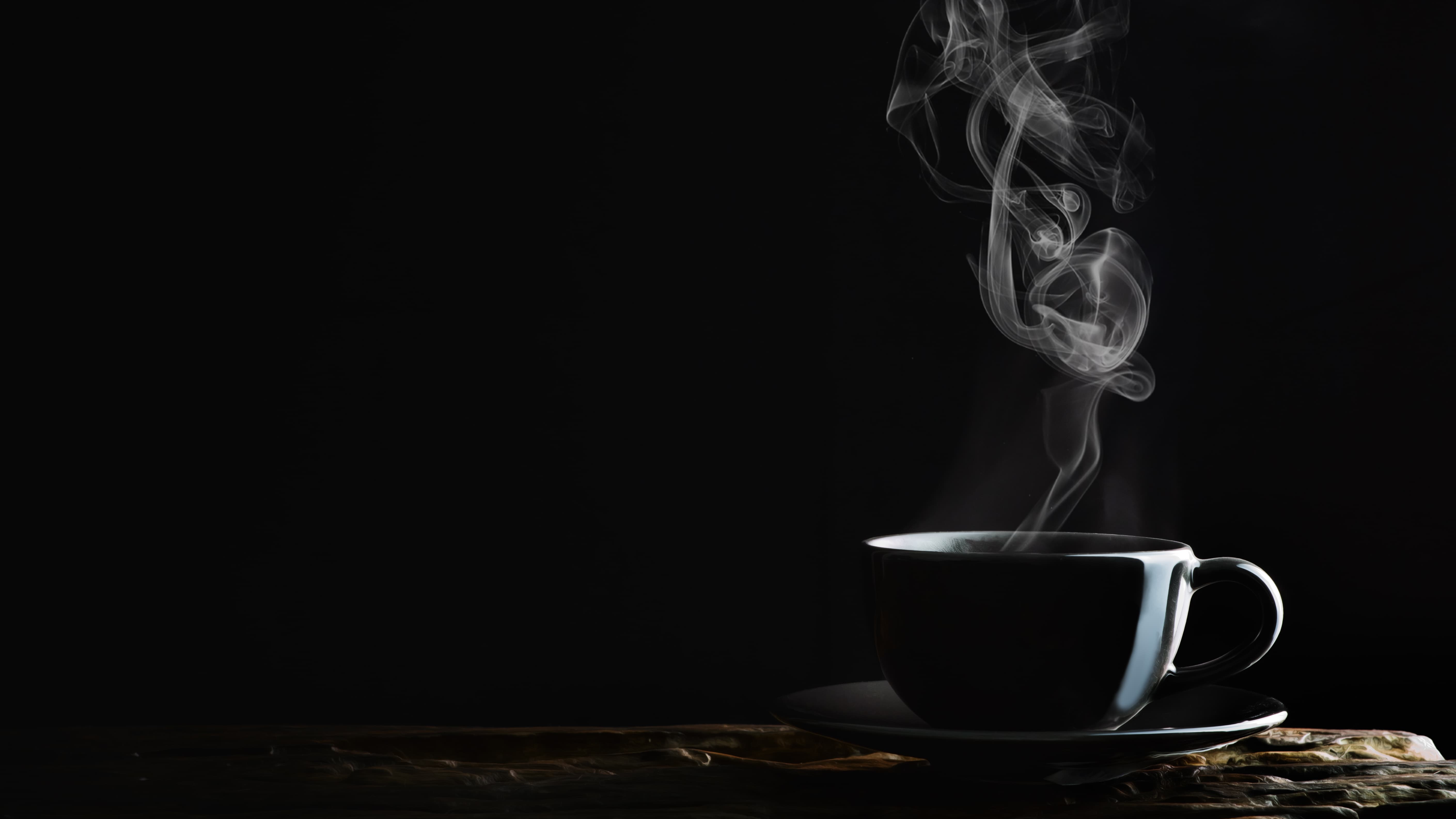 Tasse Kaffee mit Dampf Schwarze Kaffeetasse mit aufsteigendem Dampf auf dunklem Hintergrund.