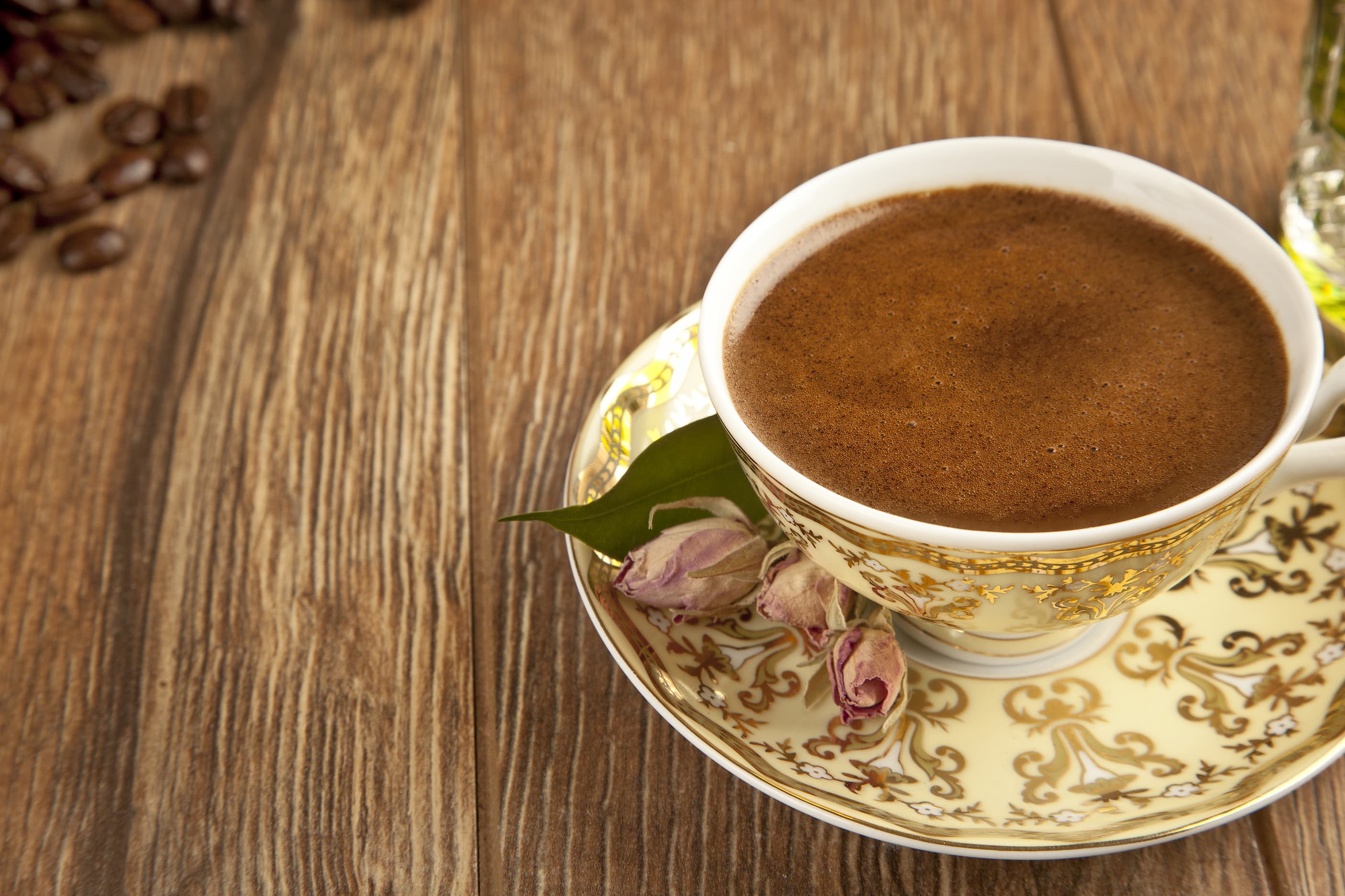 Türkischer Kaffee in verzierten Porzellantassen Türkischer Kaffee in traditioneller Porzellantasse auf Untertasse mit Rosenblättern.