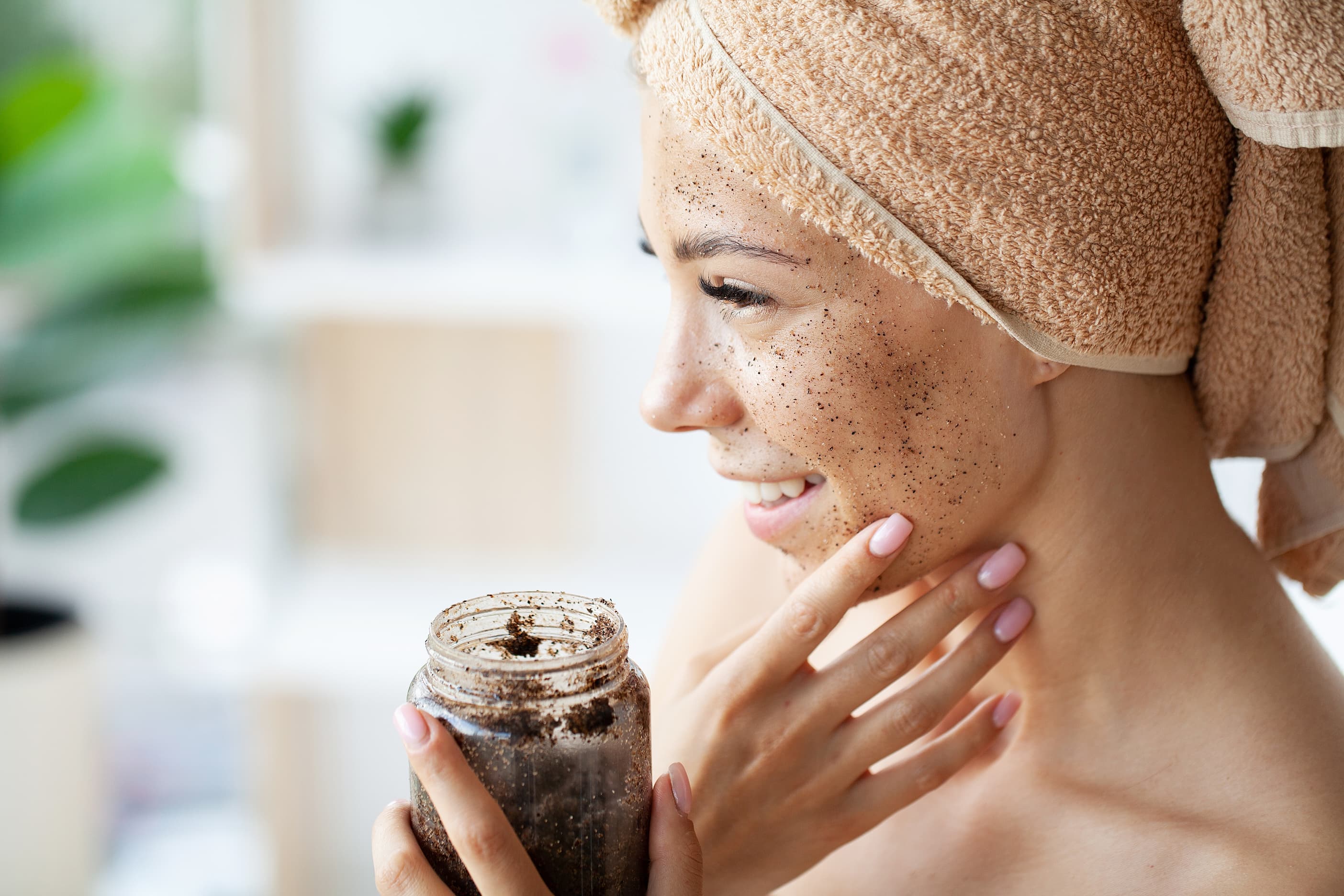Kaffeepeeling im Gesicht Frau trägt Kaffeepeeling im Gesicht auf, Hautpflege mit Naturkosmetik.