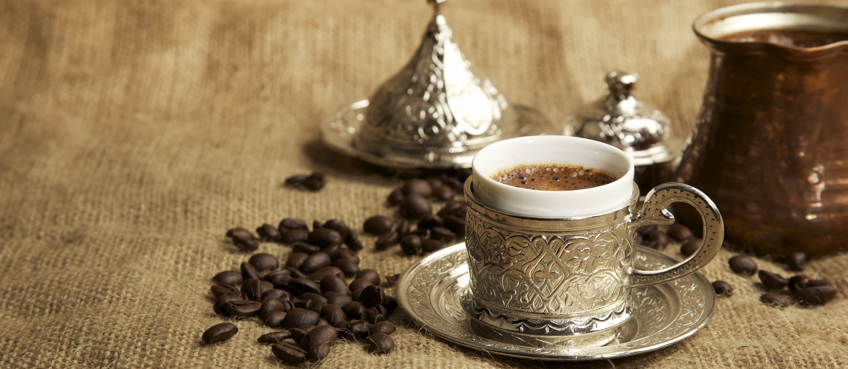 Orientalischer Kaffee im verzierten Silberbecher Eine Tasse orientalischer Kaffee im traditionellen Silberbecher mit Untertasse und Kaffeebohnen.