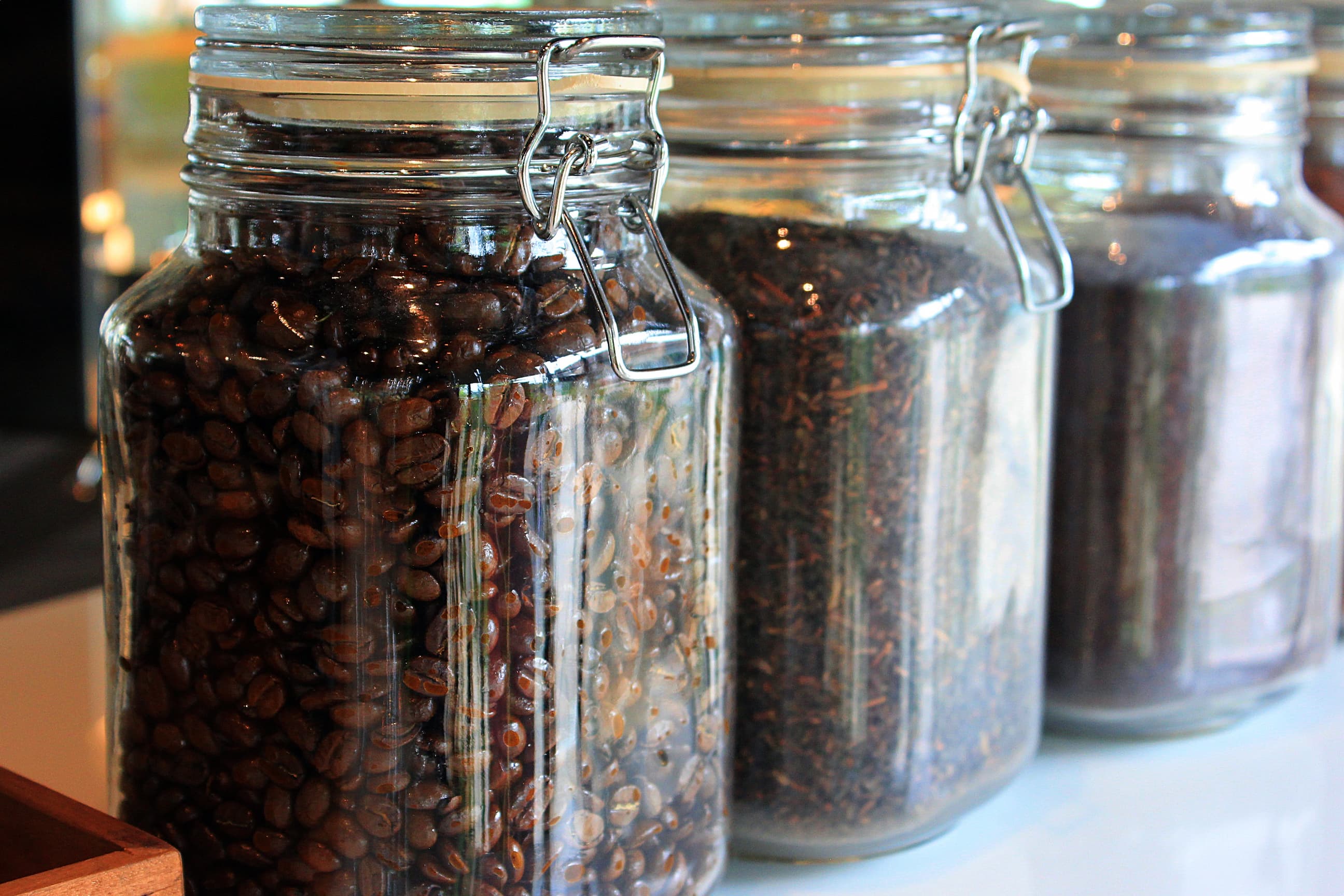 Kaffeebohnen im Aufbewahrungsglas Große Gläser mit Kaffeebohnen und Tee, verschlossen mit Metallbügeln.