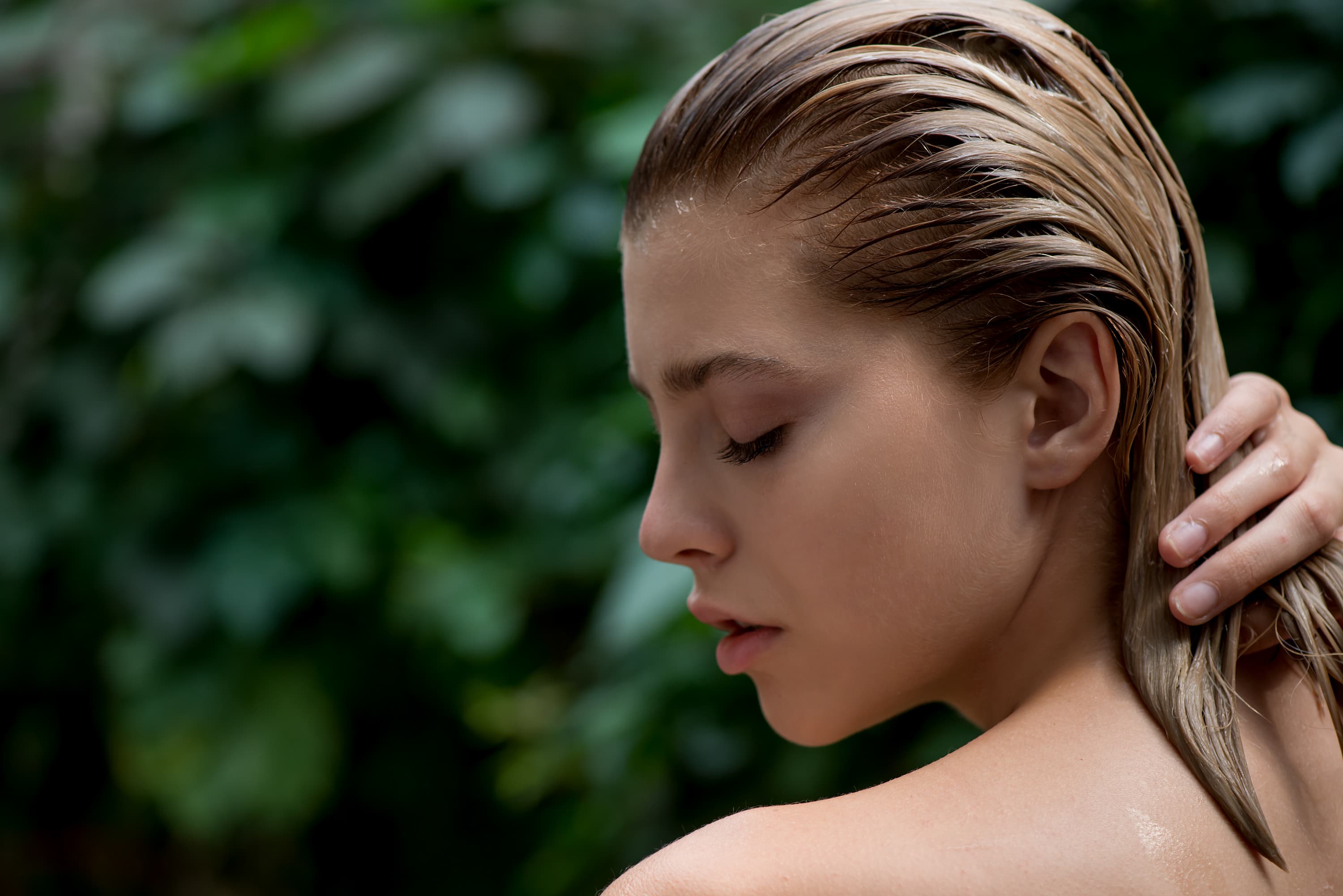 Frau mit nassen Haaren in der Natur Portraet einer Frau mit nassen Haaren vor unscharfem gruenem Hintergrund.